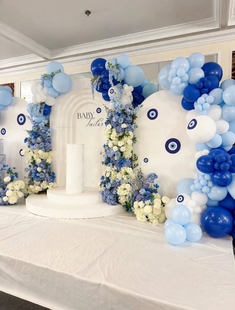 Side view of an evil-eye arch backdrop with blue balloons and blue and white florals
