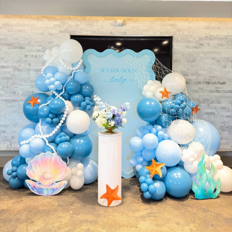 Blue and white balloon garlands with a seashell, starfish and sea-glass accents around a light blue backdrop panel