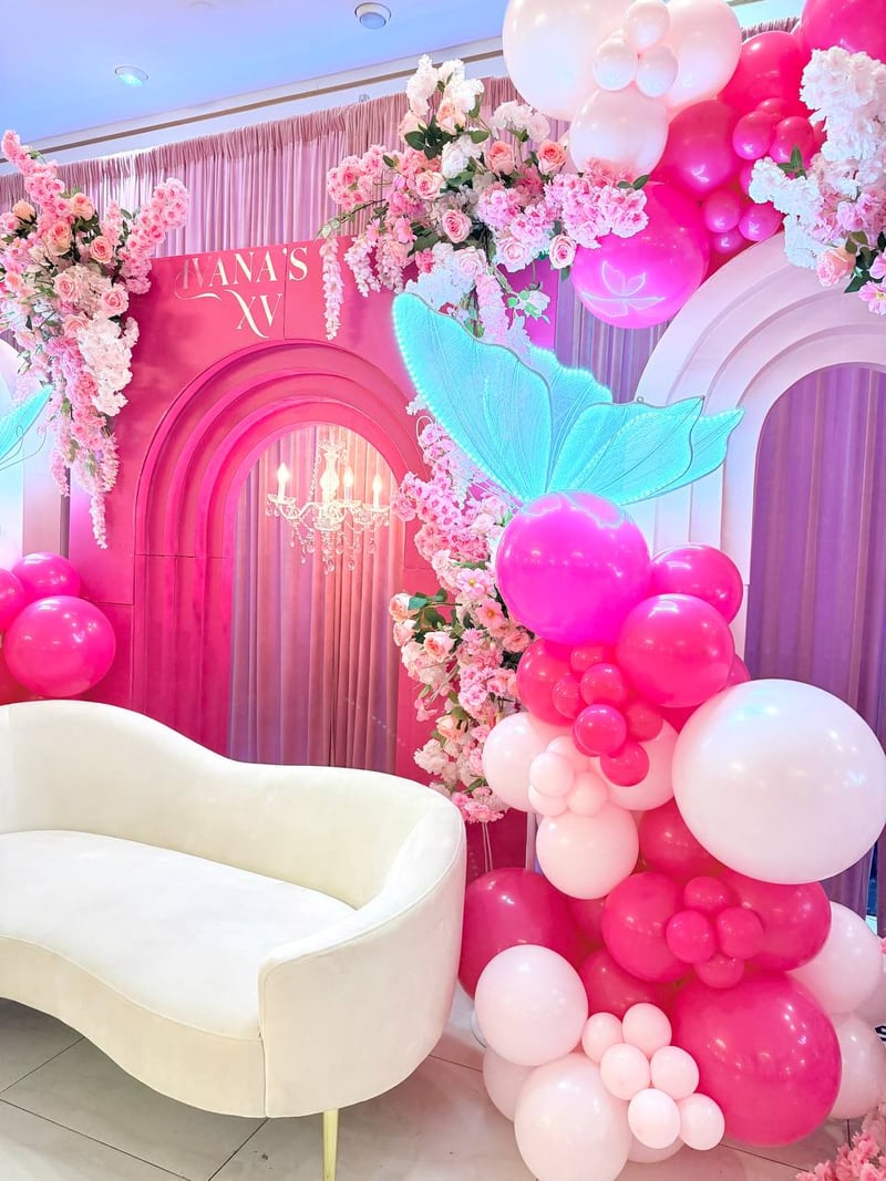 Hot pink and blush balloon column with butterflies, pink arches, florals and a cream sofa
