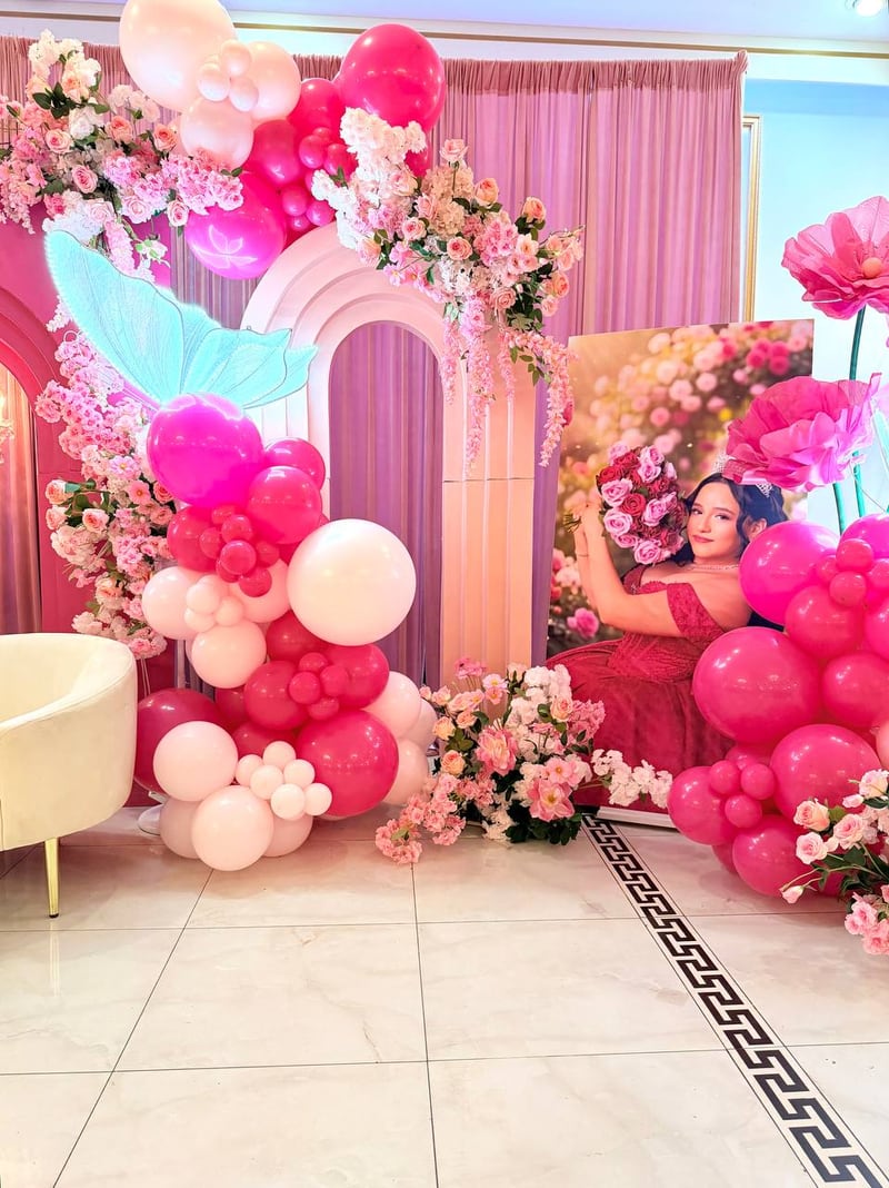 Hot pink and blush balloon column with an illuminated butterfly, pink arches, floral garlands and a framed portrait panel