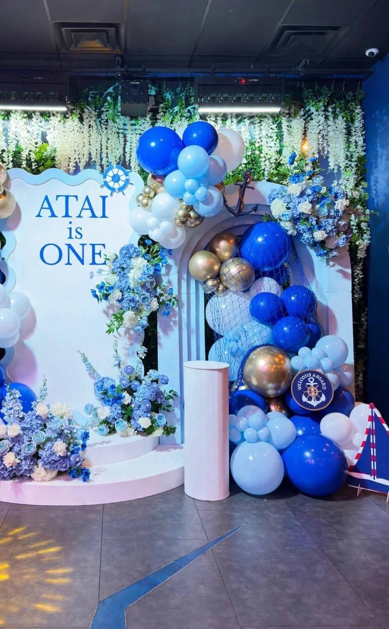 Close view of blue, navy and gold balloons and white florals around a nautical backdrop